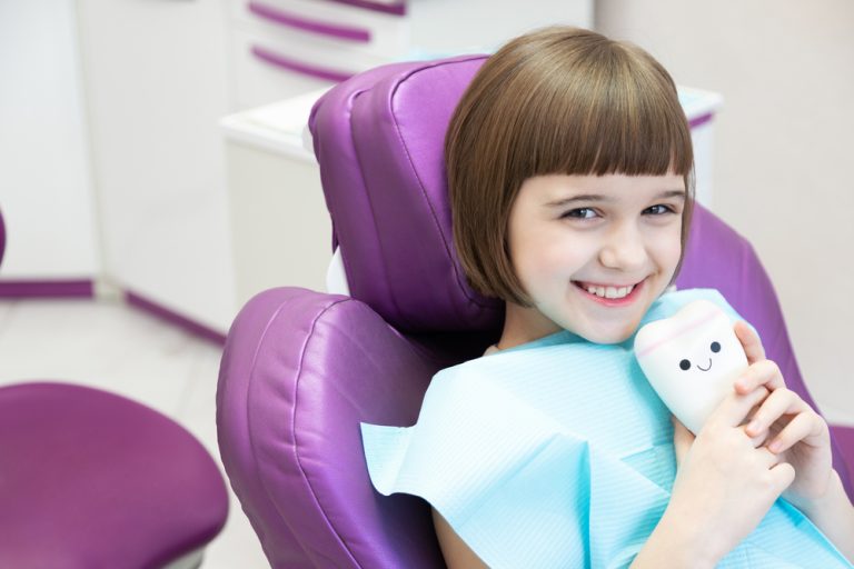Children's Dentist showing dental crown to child